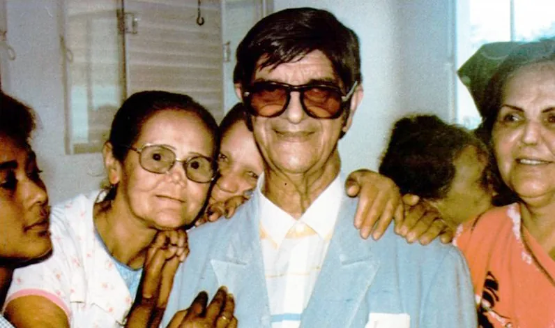 Chico Xavier rodeado de pessoas em um gesto de carinho e acolhimento